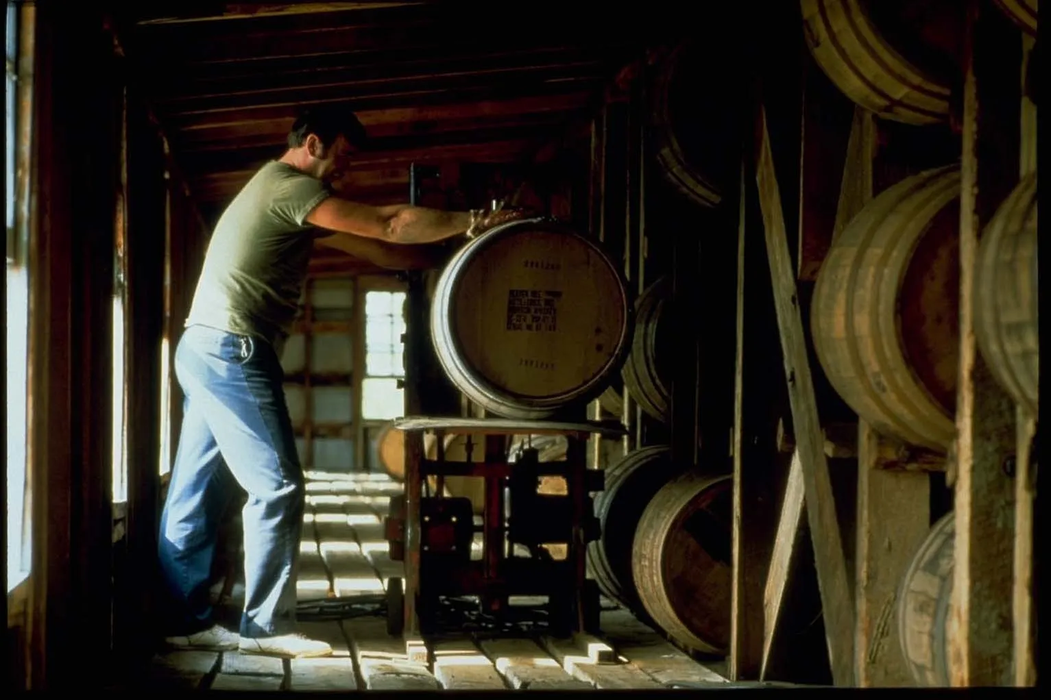 A worker rolling a bourbon barrel inside a rickhouse at Heaven Hill Distillery in Bardstown